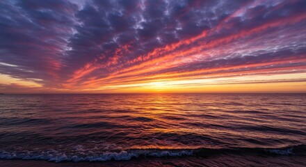 Wall Mural - Vivid sunset over the ocean, with colorful clouds streaking across the sky and reflecting on the water's surface.