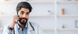 © Prostock-studio - Online consultation with doctor, health care and gadgets during covid-19 lockdown. Smiling young arabian bearded guy in white coat at table with laptop, speaks on phone and makes notes in clinic