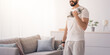 © Prostock-studio - Covid-19 quarantine and leisure activities, sports and exercise at home for healthy lifestyle. Smiling handsome arabian bearded millennial man raises dumbbells, on living room interior background