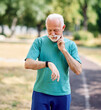 © Lumos sp - Smiling active senior man jogging exercising taking a break in the park, senior athlete checking her heart rate and performance with smartwatch