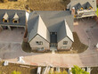 Drone view of a newly completed, large, double fronted family home on a rural housing development site in Britain. The detached garages can be seen. The lawns, yet to be laid.