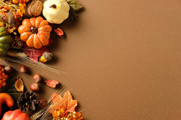 Wall Mural - Autumn flat lay with pumpkins, pinecone, acorn, nut, leaf, wheat on brown background. Left side decorated, right side blank for fall, Thanksgiving or seasonal design