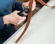© Михаил Решетников - A woman makes holes in a leather belt. Leatherworker's workshop.