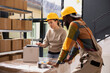 © DC Studio - Coworkers in coveralls and hardhat managing inventory control on laptop, product handling and packaging for dispatch. Preparing parcels for online shopping shipment, logistics systems.