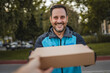 © Miljan Živković - Smiling delivery man delivering package to customer