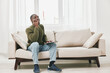 © SHOTPRIME STUDIO - Thoughtful Black man working on a laptop while sitting on a comfortable couch in a stylish room, contemplating ideas and productivity