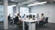 © Muhammad - Blurred image of a modern office interior with people working at desks and overhead lighting. The focus is soft, emphasizing the overall atmosphere.