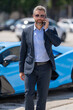© Volodymyr - Business man outdoors. Rich business man enjoying success. Luxury businessman in elegant suit. Rich man front of expensive car. Luxury business travel. Confident rich business man in a classic suit.