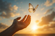 © NongEngEng - AI generated conceptual photography of a human hand releasing a delicate butterfly into glowing sunset sky symbolizing freedom peace hope emotional healing transformation and new beginnings