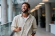 © AspctStyle - Smiling young man in casual shirt walking indoors with a joyful expression, looking confident and relaxed inside a bright modern hallway with natural light