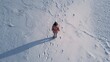 © touseef - Aerial view of a girl walking in fresh snow leaving footprints, winter outdoor activity scene with copy space in a cold frosty landscape
