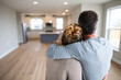 © Emanuel - New homeowners hugging in empty living room