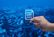 Hand holding document flat icon in fingers over modern city tower, street, expressway and skyscraper, Technology internet online concept