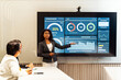 © artitwpd - Professional presents analytics dashboard on large screen in modern meeting room, explaining data, charts, metrics, and statistics. Business strategy discussion supported by report presentation.