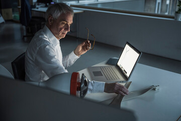 Technician holding eyeglasses and examining rotor blade at office