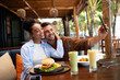 © NDABCREATIVITY - Happy couple shares a moment and a tasty meal at a charming outdoor eatery during their getaway