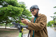 © Chanakon - Young Asian man rent the scooter EV scan by smartphone. Sustainable save energy lifestyle. Commute and carbon neutral transportation. Asian tourist man put on helmet ride the scooter EV