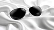 © Banyu - Aviator sunglasses resting elegantly on folds of luxurious white silk fabric surface