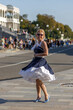 A girl with blond hair dressed in vintage nautical style dresses on the embankment of the river station, port.