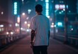 © Wang - A man in a white t-shirt walking on a brightly lit street at night.