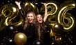 © ty - Happy gorgeous girls in stylish sexy party dresses holding gold 2026 balloons, having fun at New Year's Eve Party.