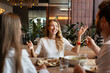 © Maria Vitkovska - Friends enjoying pizza and salad, talking and gesturing in restaurant