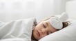 © haris - A young child sleeps peacefully in bed, a cool compress on their forehead, suggesting illness or fever.