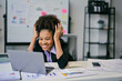 © Parichat - Excited African American businesswoman looking at laptop at office desk