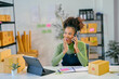 © Parichat - Young african american woman managing online store orders talking on phone surprised by good news