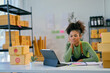 © Parichat - Stressed young african american woman managing online business from tablet in warehouse