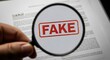 © MdLutfur - Magnifying glass focusing on the word fake stamped on a document, highlighting the concept of deception, misinformation, and the importance of verification