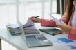 © PaeGAG - Businesswoman reviewing documents and working at office desk