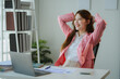 © PaeGAG - Happy businesswoman relaxing with hands behind head at office desk