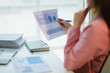 © PaeGAG - Businesswoman analyzing financial charts and graphs at office desk