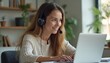 © Viktor - Young woman with headset actively participates in online class work meeting. Studies works from home, using laptop for video conference call. Focused, engaged, takes notes interacting with teacher