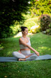 © sepy - Confident woman sitting on yoga mat and doing yoga in the backyard