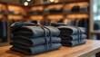 © Viktor - Neatly stacked dark gray hoodies sit on a wooden table in a retail store. Apparel, clothing, comfort, and warmth for autumn and winter seasons. Simple, elegant, modern merchandise display.
