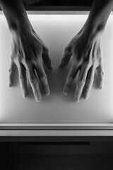 Wall Mural - Artistic black and white close-up of hands on illuminated surface