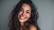 © Johannes - close up face of young woman with beautiful smile isolated on grey wall with copy space successful multiethnic girl latin woman looking at camera against gray wall with a big whitening teeth smile no