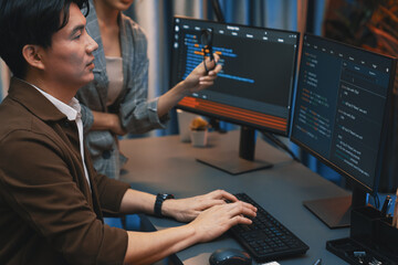IT developers discussing with point to intelligent website development coder system running data online two screens information technology at neon light room at modern office. Infobahn.