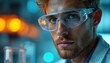© Viktor - Close-up portrait of young Caucasian scientist, light blonde hair, short beard, clear safety glasses. Man looks directly at viewer. Laboratory background with blue, orange bokeh lights. Research