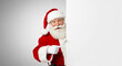 © Ashish - Jolly santa claus peeking around a white blank board with a friendly smile and pointing finger