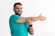 © Prostock-studio - Cheerful young male athlete with beard does stretching for arms, exercises for muscular, fitness for body in living room interior, free space. Health care, workout at home, during covid-19 pandemic