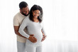 © Prostock-studio - Satisfied millennial black handsome hugs pregnant wife in bedroom interior and look at belly on window background. Couple awaiting baby, cute parents-to-be together at home, family enjoy tender moment