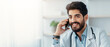 © Prostock-studio - Therapist calls to patient, medical service and family doctor during COVID-19 outbreak. Smiling 30s arabian bearded guy in white coat at table with laptop, speaks on phone in office interior in clinic
