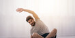 © Prostock-studio - Yoga, fitness and pilates at home, online lesson during covid-19 pandemic. Smiling arabian bearded young guy doing warm-up or stretching looks at laptop in living room, on floor with bottle of water