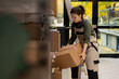 © DC Studio - Female staff member managing cardboard boxes storage on shelving units, ensuring parcels are packaged correctly for shipment. Small delivery services for e-business operations.