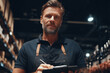 © Maksym - Confident man in apron holding clipboard in warehouse
