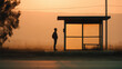 © rungnapha - Silhouette traveler bus stop rural sunrise fog waiting solitary road calm dawn orange mist countryside shelter backpack male
