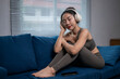 © Apichat - Young asian woman listening music with headphones on sofa at home